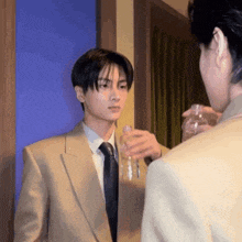 a man in a suit and tie is holding a bottle of water and looking at another man .