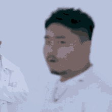 a man with a beard is wearing a white shirt and a white jacket