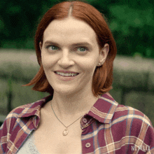 a woman wearing a plaid shirt and a necklace with the word netflix on it