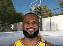 a man with a beard is smiling in front of a basketball court