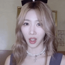 a blonde woman wearing a pearl necklace and a black bow on her head