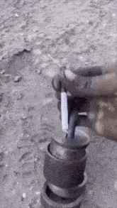 a person is holding a cigarette and a piece of metal