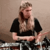 a woman is playing drums in a black shirt .