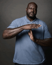 a man in a blue shirt is making a stop sign with his hands