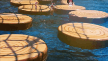 a group of people standing on wooden blocks in a pool