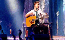 a man playing a guitar on a stage with a crowd behind him