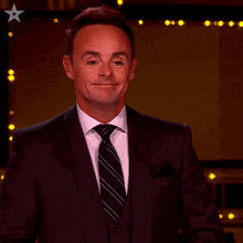 a man in a suit and tie is clapping his hands and smiling