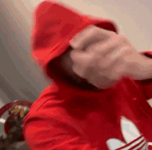 a person in a red hoodie is covering their face with their hands .