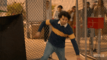 a man in a blue and yellow striped shirt is throwing a ball in front of a netflix sign
