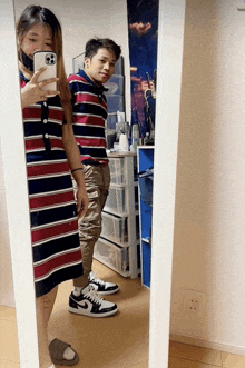 a man and a woman are taking a selfie in a mirror