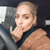 a woman blowing a kiss while sitting in the driver 's seat of a car