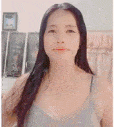 a woman with long black hair is wearing a grey tank top