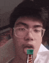 a man with glasses is drinking from a bottle