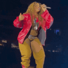a woman wearing a red jacket and yellow pants is dancing on a stage