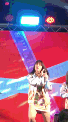 a woman singing into a microphone on a stage with a sign behind her that says ' a '