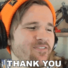 a man wearing an orange beanie and headphones is saying thank you