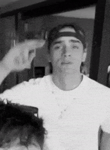 a black and white photo of a man wearing a baseball cap and a white shirt .