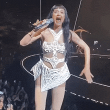 a woman in a white dress is singing into a microphone on stage .
