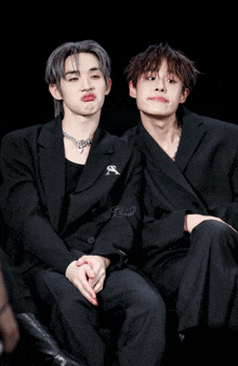 a couple of boys sitting next to each other with one wearing a jacket with the letter s on it