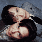 two men laying on top of each other with one wearing a plaid suit and tie