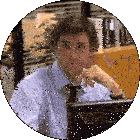 a man in a blue shirt and tie is sitting in front of a computer monitor