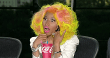a woman with bright yellow hair is drinking a coca cola .