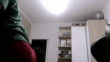 a person in a green shirt is standing in a room with a globe on the shelf