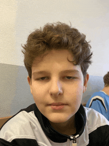 a young boy wearing a black and white nike jacket looks at the camera with a serious look on his face