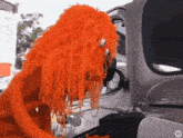 a stuffed animal with orange hair is looking into a car