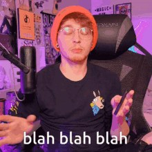 a man wearing an orange beanie and glasses is sitting in a spawn chair
