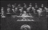 a man stands at a podium in front of a crowd of people