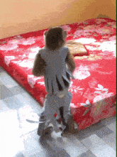 a monkey is standing on a bed with a floral sheet