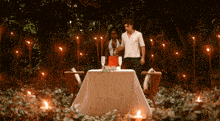 a man and a woman are standing in front of a table surrounded by candles