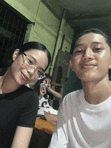 a man and a woman pose for a picture with a bowl of food in the background