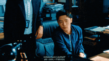 a man in a blue shirt is talking to another man in a black suit