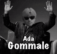 a man in a suit and tie is sitting in a chair with his hands in the air and the words ada gommale above him