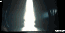 a person is standing in a dark room with a light coming out of the ceiling .