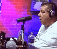 a man wearing headphones talks into a microphone in front of a brick wall