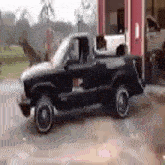 a black truck is parked in front of a building .