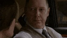 a man in a suit and tie is sitting in a car with the words " i will " written in red
