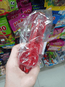 a person is holding a red gummy penis in front of a display of haribo