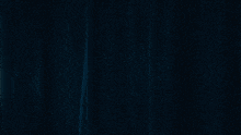 a woman is standing in front of a window with a blue curtain behind her .