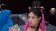 a girl in a pink dress is holding a green bottle in her hand