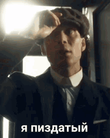 a man in a suit and hat wipes his forehead with his hand in front of a sign that says ' i '