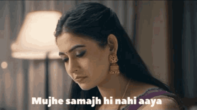 a woman wearing a purple saree and gold earrings says 