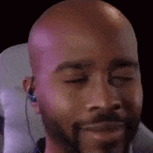 a close up of a bald man with a beard wearing headphones and smiling .