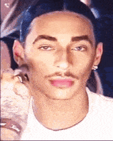 a man with a mustache is getting his face painted by a woman .