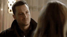 a man and a woman are looking at each other and the man is wearing a black jacket .