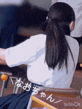 a girl is sitting at a desk in a classroom with japanese writing