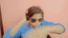 a man wearing headphones and sunglasses is dancing in front of a pink wall